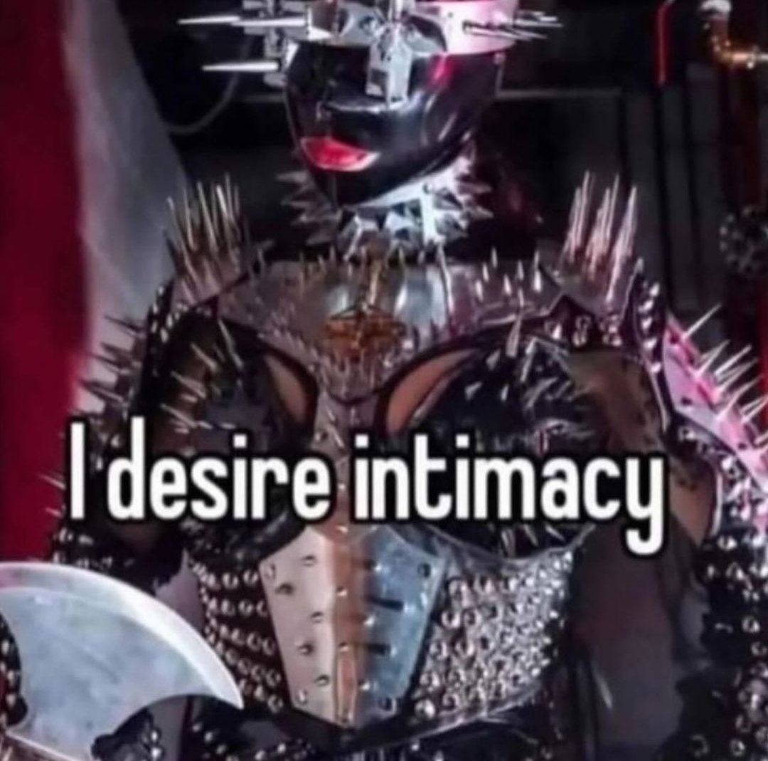 The meme is a humorous image of a person in a BDSM (Bondage, Discipline, Dominance, Submission, Sadism, and Masochism) costume, specifically a "BDSM fetishist" or "kinkster" costume. The image is captioned "I desire intimacy" in a dry, ironic tone, suggesting that the person is seeking emotional connection despite their provocative attire. The meme is likely intended to be humorous and satirical, poking fun at the idea of seeking intimacy in a seemingly provocative context.